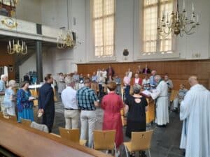 Beeld van de schriftlezing door Dirk van Leeuwen, emeritus vicaris-generaal van de Church of England. Onder de gasten was ook commissaris van de koning Hugo de Jonge (4e van links)