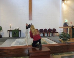 Het dekzeil wordt voorafgaand aan de dienst van het doopbassin verwijderd.